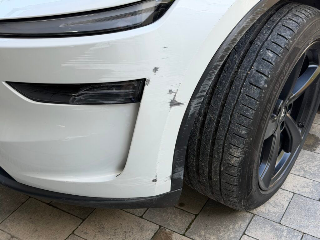 Pare-chocs avant gauche d'un Tesla Model Y blanc rayé par une remorque