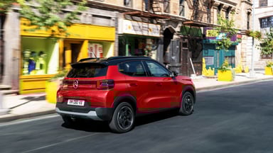 Citroën ë-C3 électrique en circulation en ville, vue arrière trois-quarts