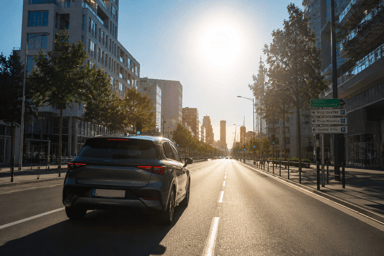 Voiture électrique roulant sous un fort soleil lors d'un épisode de canicule en ville.