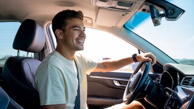 Jeune conducteur souriant au volant de sa première voiture, ceinture de sécurité bouclée, par une journée ensoleillée