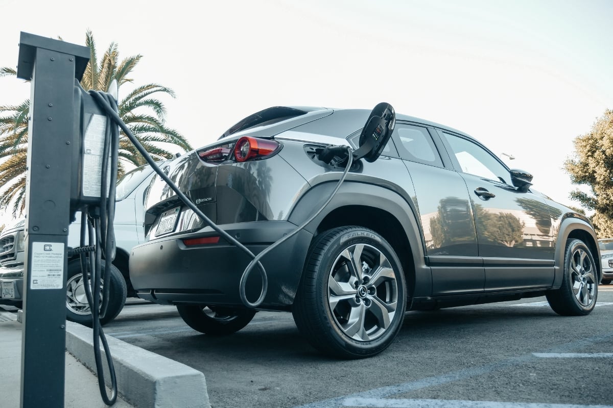 Le SUV électrique Mazda MX-30 gris en recharge sur une borne publique, un exemple de véhicule à petite autonomie pour un usage urbain.
