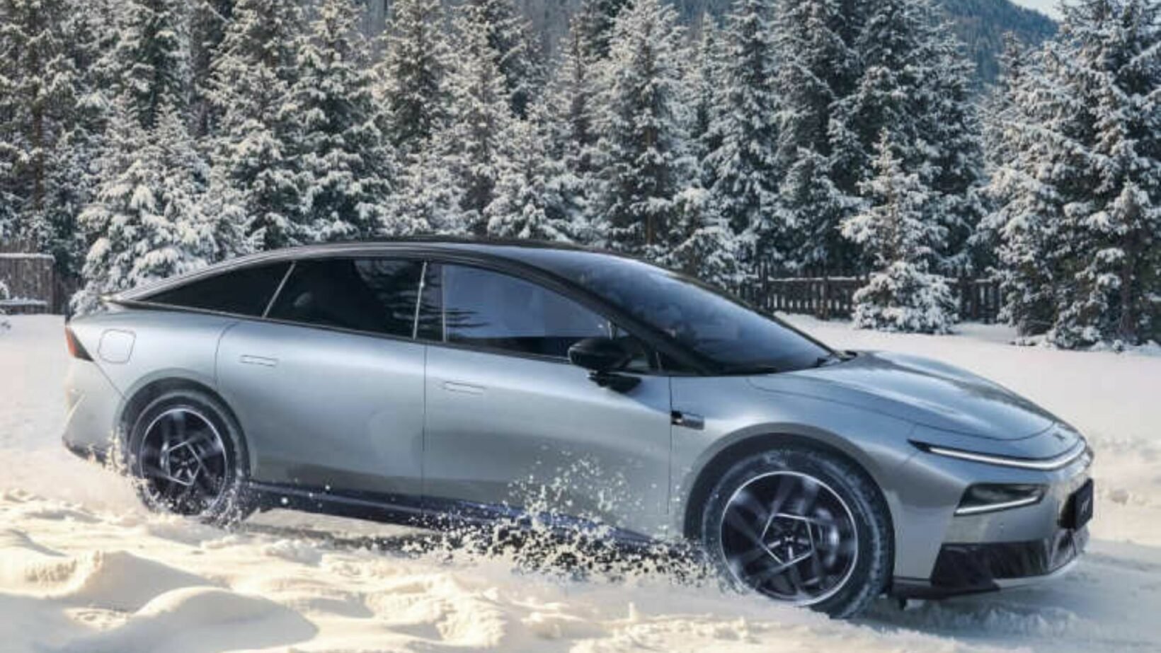 XPeng P7+ grise roulant dans la neige, berline électrique vue de profil avec forêt enneigée en arrière-plan
