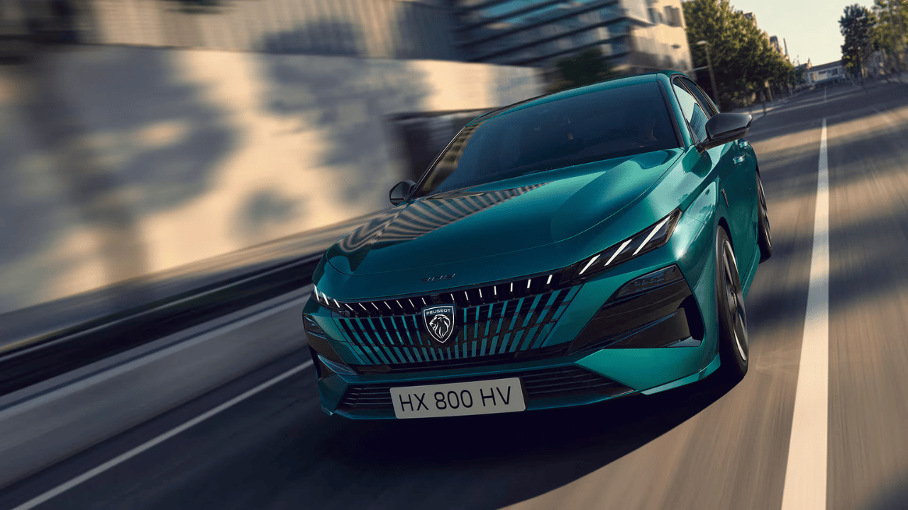 Peugeot 308 électrifiée turquoise roulant sur route urbaine en fin de journée