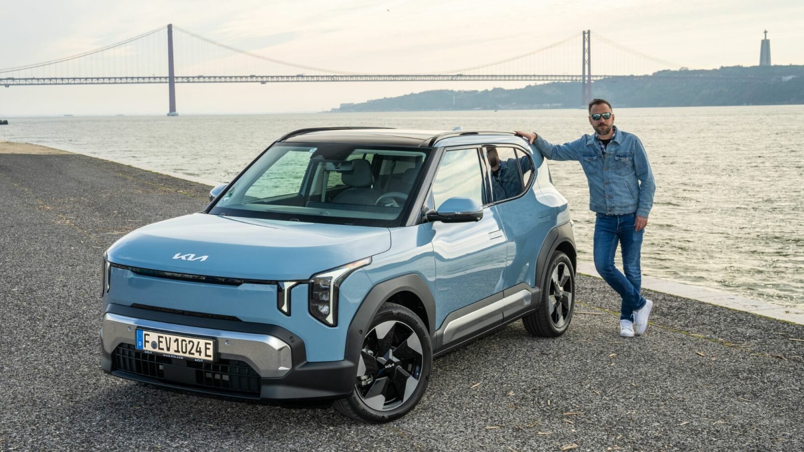 Victor Diakov avec la Kia EV2 devant le pont du 25 avril à Lisbonne