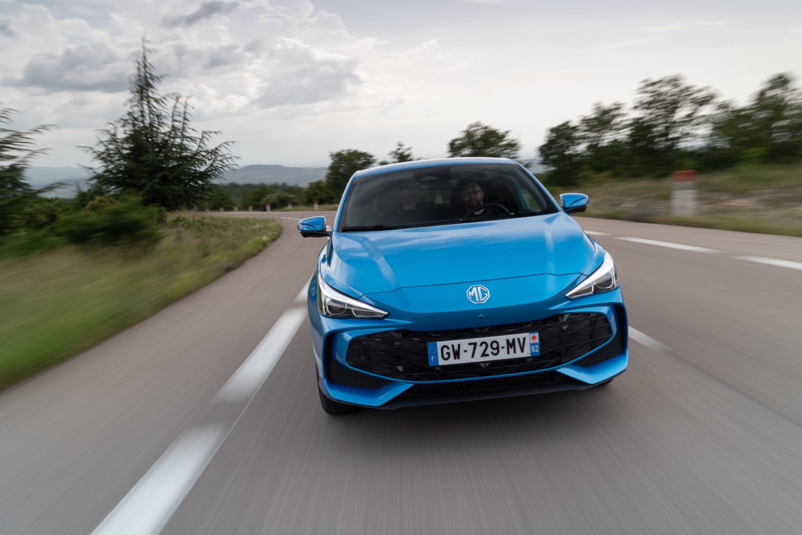 MG3 Hybrid+ bleue vue de face en roulage sur une route de campagne
