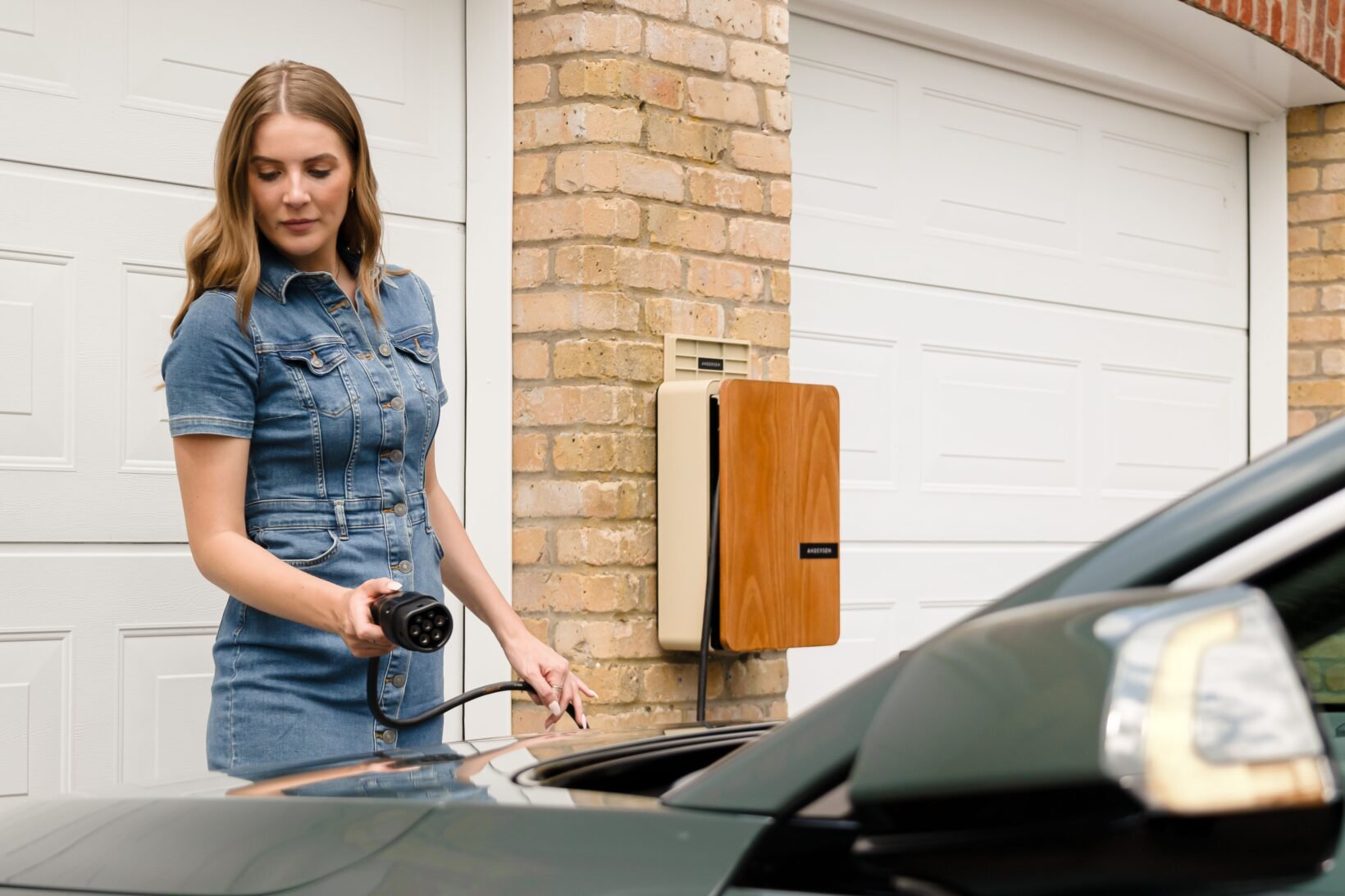 Conductrice branchant le câble de recharge de sa voiture électrique sur une wallbox à domicile