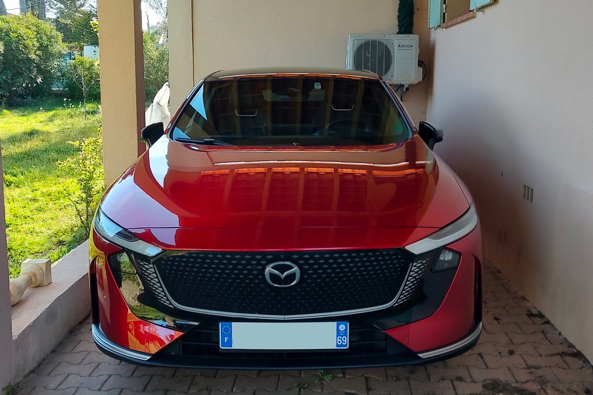 La Mazda 6e avec en arrière plan la pompe à chaleur pour la maison