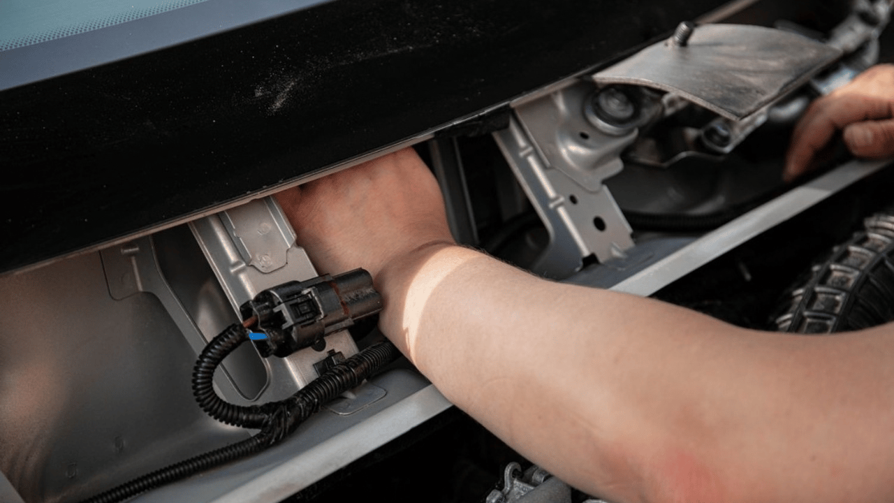 Technicien branchant un connecteur électrique d'une voiture électrique en garage