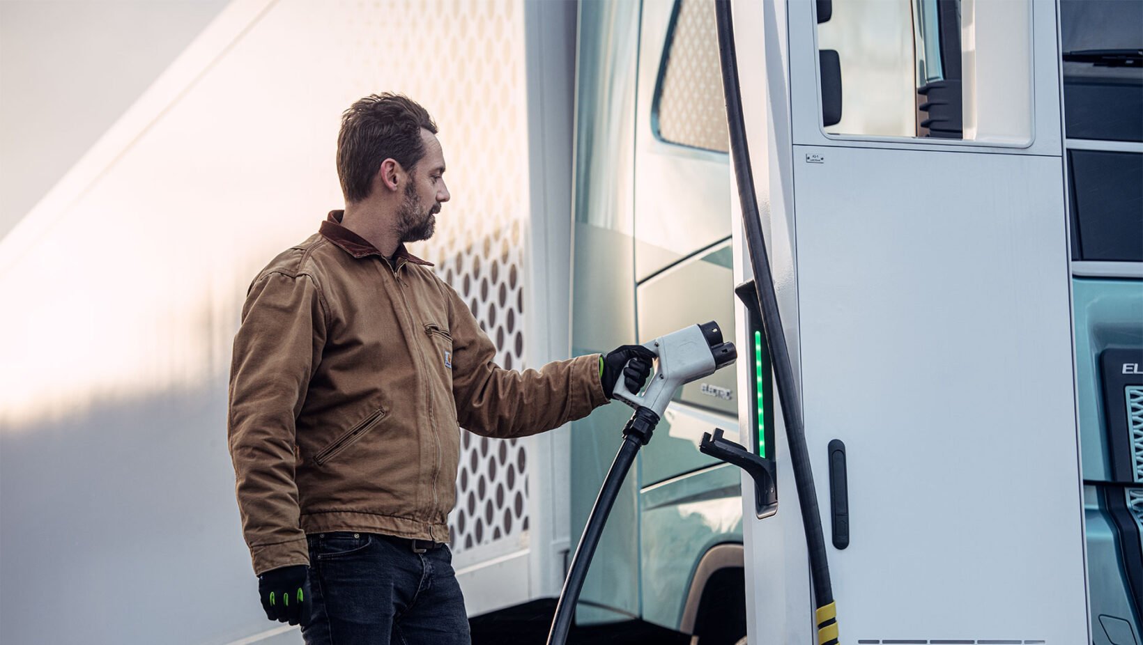 Homme rechargeant un poids lourd électrique