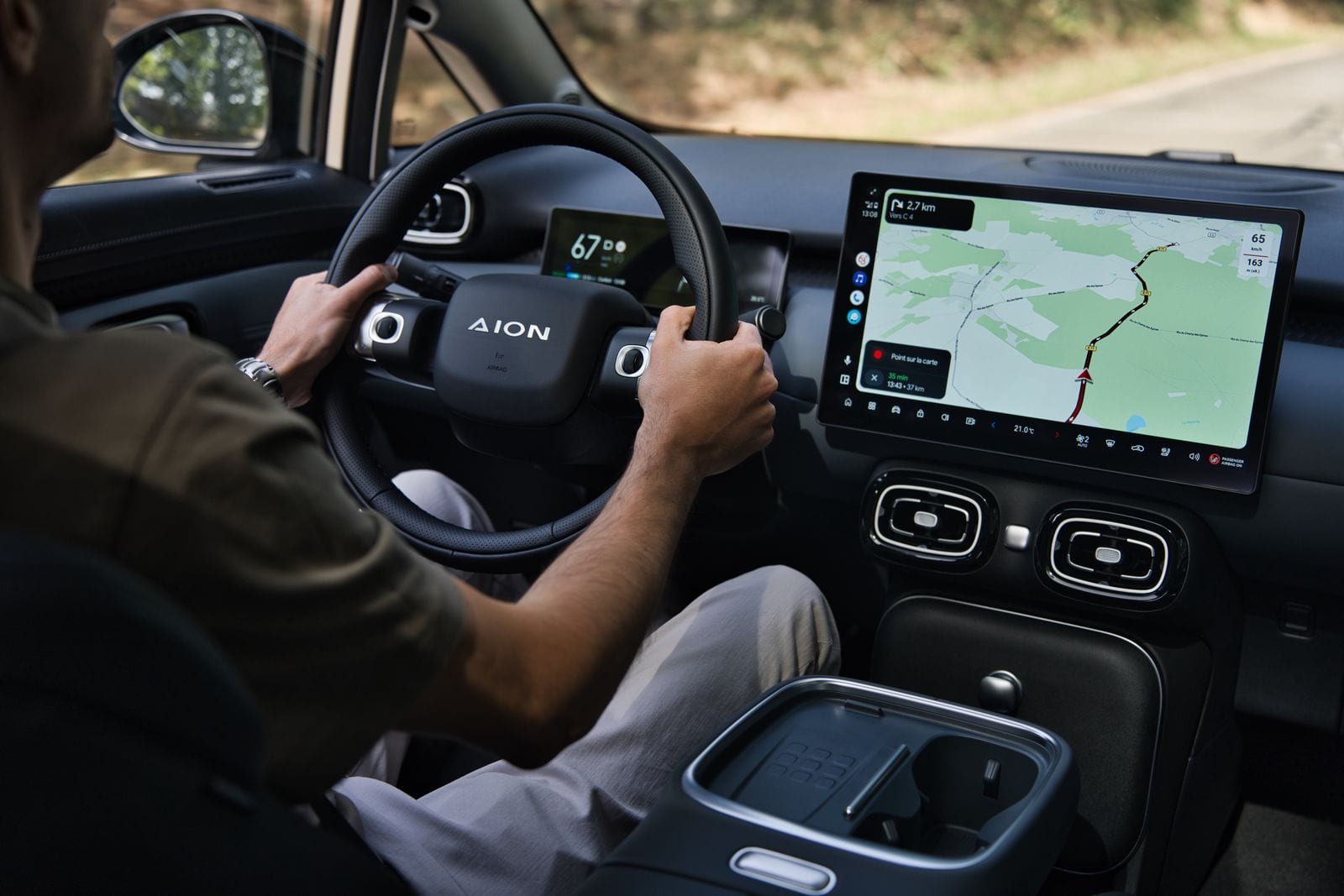 Habitacle vu du poste de conduite : volant siglé AION, combiné numérique et grand écran tactile de navigation