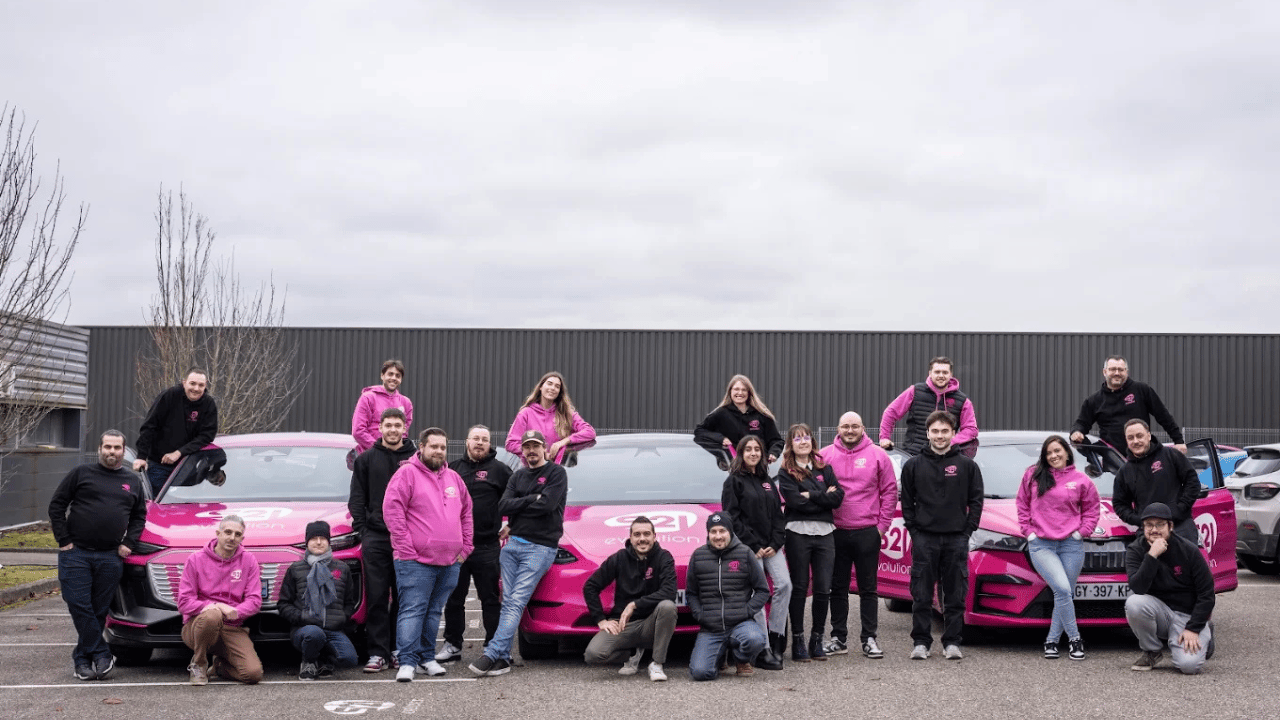 Equipe posant devant une flotte de voitures electriques sur un parking