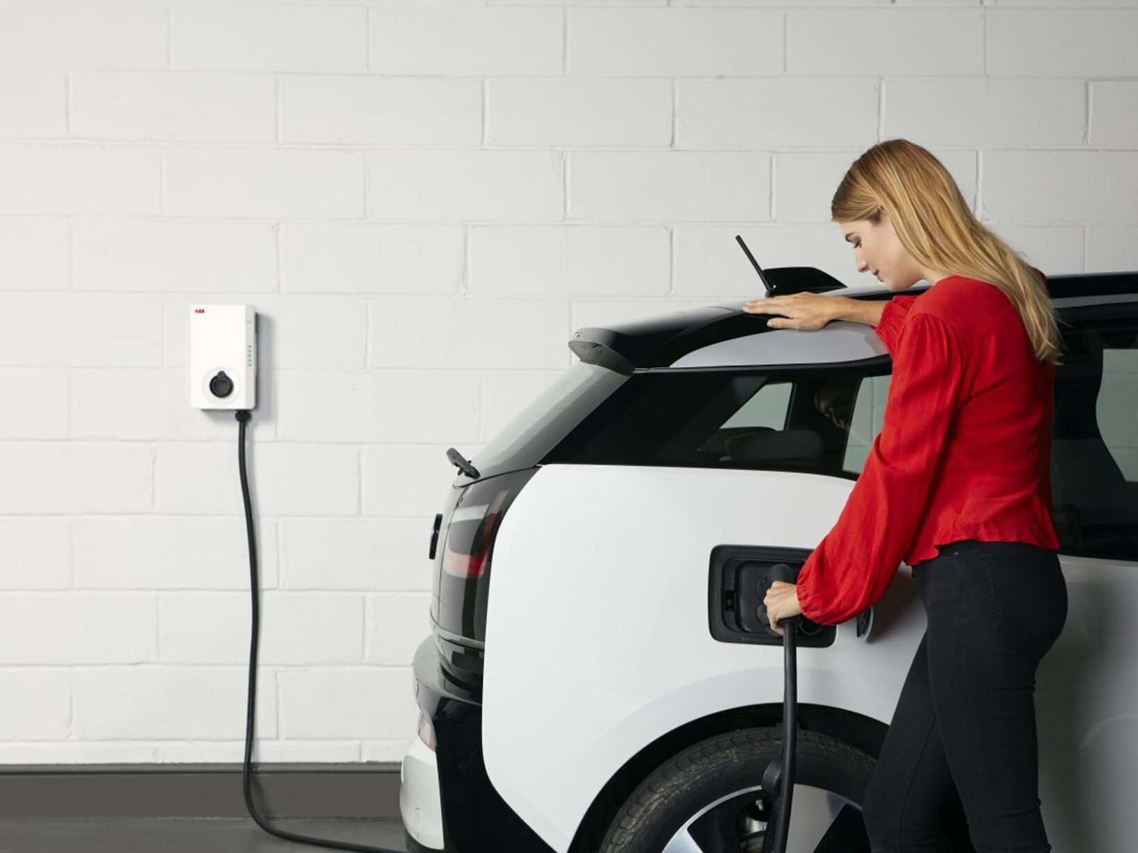 Automobiliste branchant sa voiture électrique à une borne de recharge à domicile