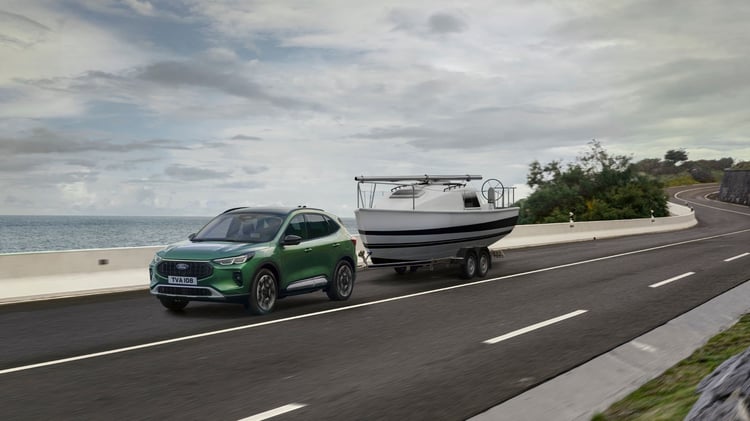 Ford Kuga hybride tractant un bateau sur route côtière, SUV hybride avec capacité de remorquage