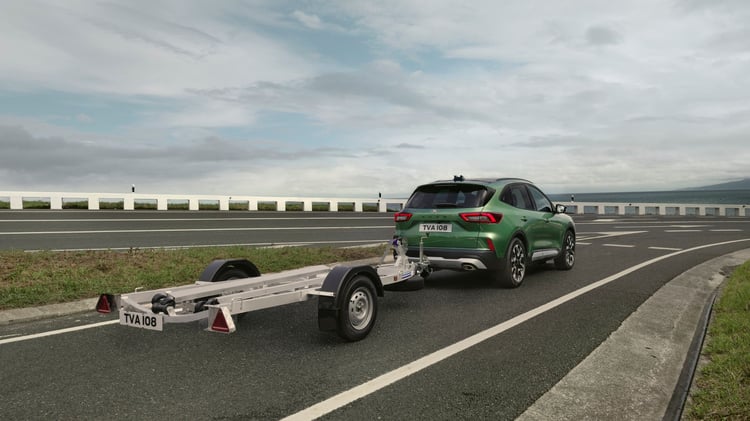 Ford Kuga hybride avec remorque sur route côtière montrant la capacité de remorquage du SUV