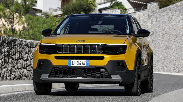 Jeep Avenger électrique jaune vue de face roulant en ville sur une rue résidentielle