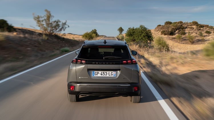 Peugeot 2008 électrique en mouvement sur route vue arrière SUV compact électrique