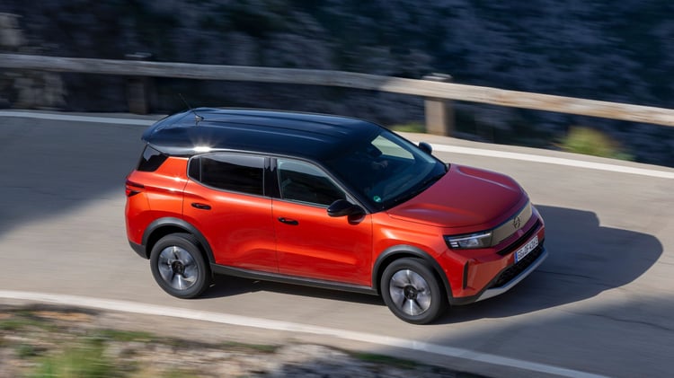 Opel Frontera électrique rouge en circulation sur route de montagne vue latérale