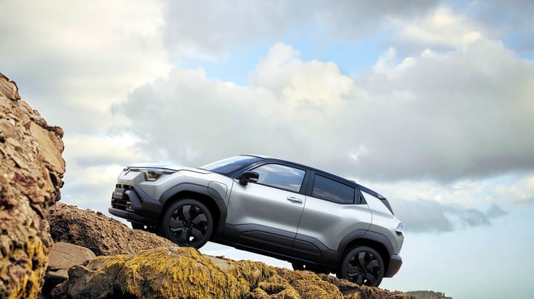 Suzuki e Vitara électrique évoluant sur terrain accidenté, vue latérale