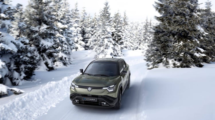 Suzuki e Vitara électrique roulant sur une route enneigée en forêt