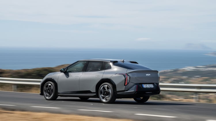 Kia EV4 Fastback électrique en conduite sur route, vue arrière trois-quarts.
