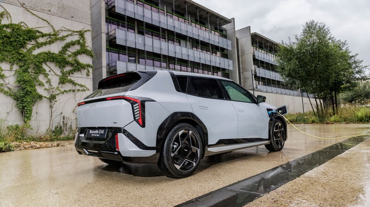 Kia EV4 vue de trois-quarts arrière en recharge, câble branché sur la prise latérale avant.