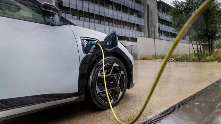 Kia EV4 en recharge avec câble branché sur la prise avant gauche, jante alliage visible.