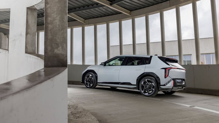 Kia EV4 vue de trois-quarts arrière stationnée, silhouette 5 portes et jantes alliage.