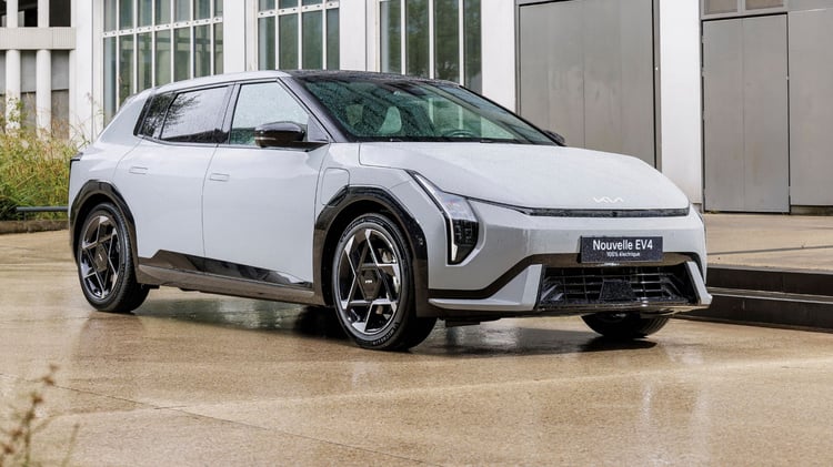 Kia EV4 100 % électrique vue de trois-quarts avant, version 5 portes avec jantes alliage 19 pouces et signature lumineuse verticale à LED.