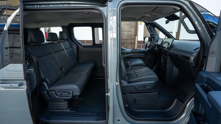 Intérieur du Kia PV5 Passenger avec porte latérale coulissante ouverte et banquette arrière trois places