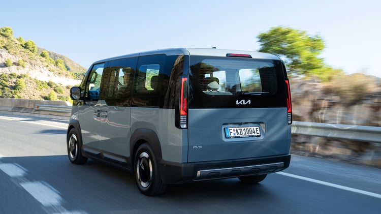 Kia PV5 Passenger électrique en roulage vu de trois-quarts arrière, van cinq places sur route
