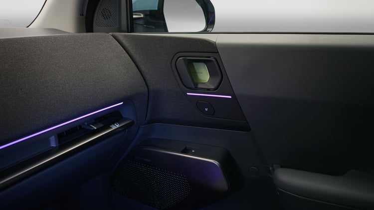 Portière passager Kia EV2 avec éclairage d’ambiance violet et haut-parleur.