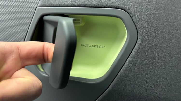 Détail d’une poignée intérieure de porte de la Kia EV2, avec le message « Have a nice day ».