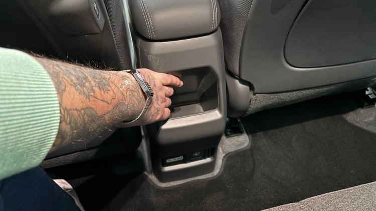 Rangements arrière de la Kia EV2 : vide-poches au dos de la console centrale et prises pour les passagers.