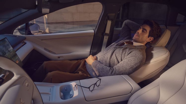 Homme allongé sur le siège passager avant d’une XPeng P7+ avec intérieur clair et écran central
