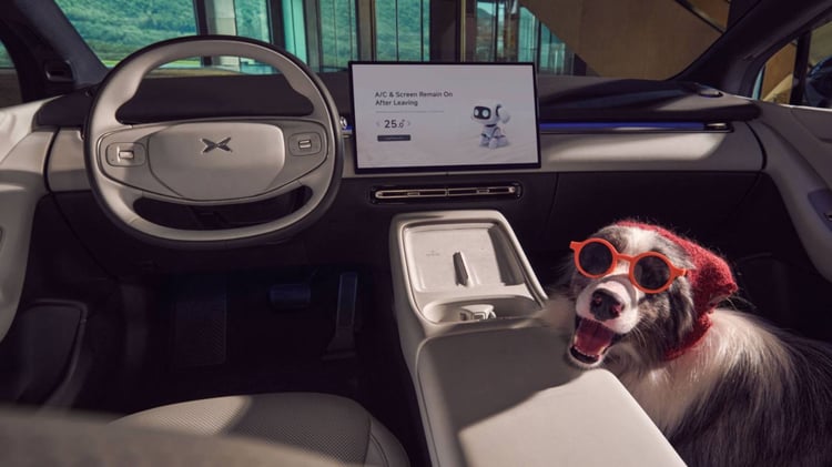 Intérieur de la XPeng P7+ avec grand écran central et un chien portant des lunettes rouges sur le siège passager