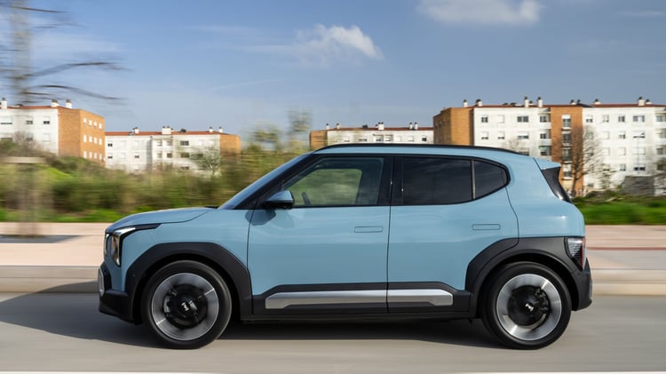 Kia EV2 électrique bleu givré en mouvement vue de profil sur route