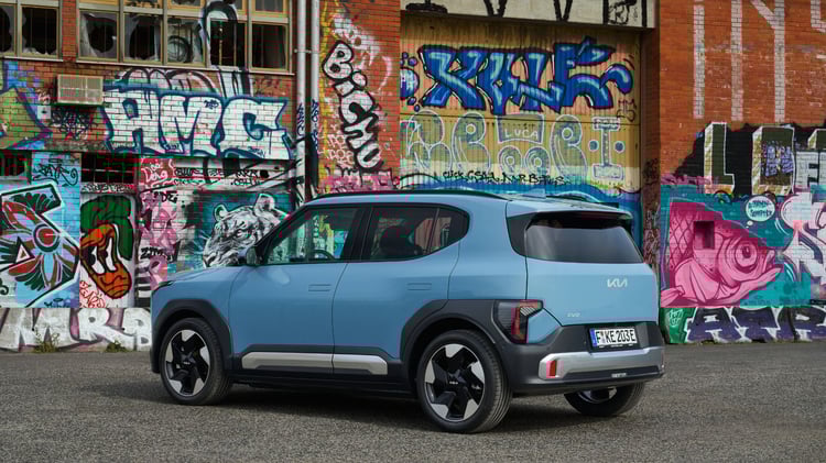 Kia EV2 électrique bleu givré finition Earth vue profil en ville devant mur graffiti