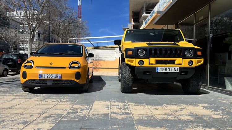 Renault Twingo E-Tech électrique jaune Mango face à un Hummer H2, comparaison de gabarit en ville