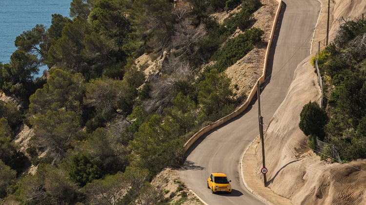 Renault Twingo électrique jaune sur route sinueuse en bord de mer