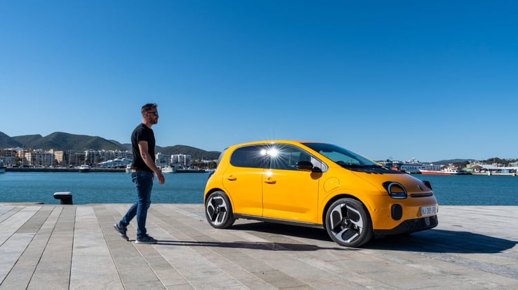 Renault Twingo E-Tech électrique jaune Mango avec jantes 18 pouces, à côté d’un homme pour illustrer ses dimensions compactes