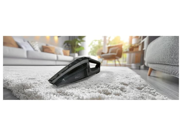 Aspirateur à main sans fil Lidl Silvercrest posé sur un tapis dans un salon