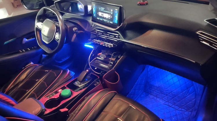 Habitacle de Peugeot 208 avec volant compact, ecran tactile central et eclairage d'ambiance bleu