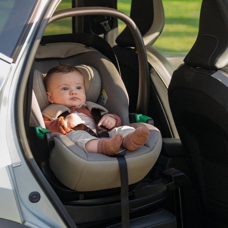 Bébé installé dans une coque Foppapedretti Disk Infant i-Size, portière du véhicule ouverte