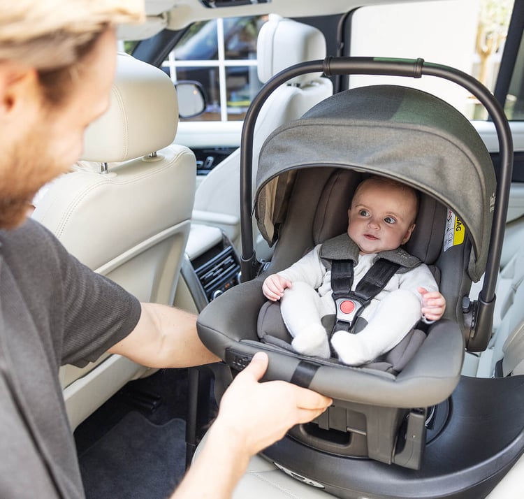 Bébé installé dos à la route dans une coque Joie Sprint, étiquette d'avertissement airbag visible