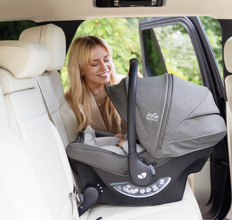 Coque Joie Sprint installée dos à la route sur la banquette, une femme veille sur le bébé