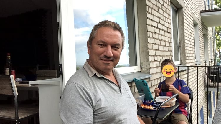 Homme souriant et enfant attablés sur un balcon lors d'une halte d'un voyage en voiture electrique