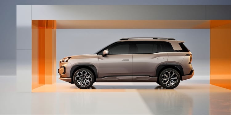 SUV électrique beige champagne vu de profil en studio, toit noir, barres de toit et jantes bi-ton