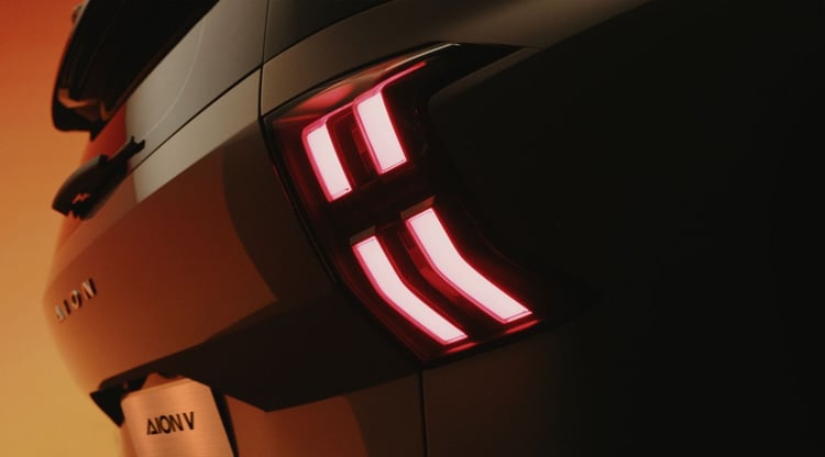 Détail du feu arrière LED de l'Aion V, signature lumineuse rouge à quatre segments et badge AION sur le hayon