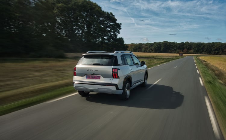 SUV electrique Aion blanc vu de trois-quarts arriere en roulage sur une route de campagne