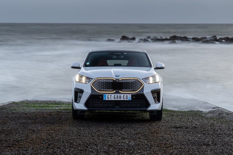 Face avant de la BMW iX2 blanche avec calandre lumineuse Iconic Glow allumée